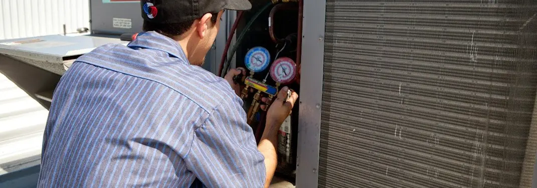 HVAC technician servicing a condenser unit in Ashland